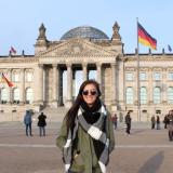A student standing in front of the building with flags 