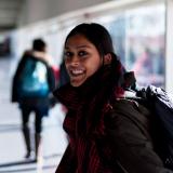 a girl standing in the airport smiling at the camera person 