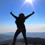 a student standing at the top of the mountain looking up 