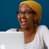 A girl using a laptop and smiling 