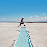 Student jumping over a little river in the salt flats