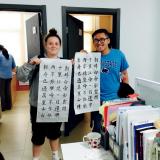 Two students holding up their Chinese character writings