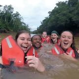 Five students in life vests swimming in an Ecuadorian river