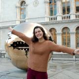 A student poses with Sphere within a Sphere, a bronze globe outside the Main Library of Trinity College.