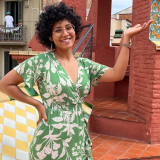 A girl smiling outdoors, wearing a green dress 