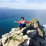 Angela Tetty with arms out sitting on rocks