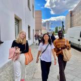 three students walking a berlin street holding bags and jackets