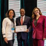 A man winning and award standing between to women