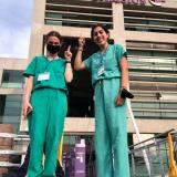 two female students in scrubs pose for a photo outside of their clinical observation