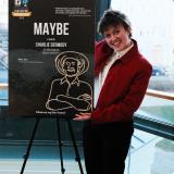 A person stands beside a film poster