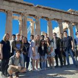 Group of people posing in front of the Parthenon under a clear blue sky. Athens field trip