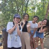 Group of female students smiling on a bridge surrounded by green trees 