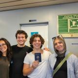A group of friends smiling and one is holding up a passport.
