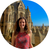 Autumn Paone posing in front of an ornate building in front of a blue sky.