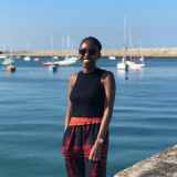 Woman smiling at a sunny harbor with sailboats in the background