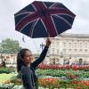 a student holding a Union Jack flag umbrella at Buckingham Palace