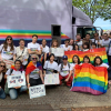 Students attend Tokyo Pride. They hold signs and rainbow flags.