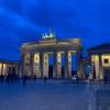 A photograph of the Brandenburg Gate with a dark blue and cloudy sky in the background.