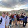9 students and the program director taking a picture with the view of the the city of Granada in the middle of a hike.