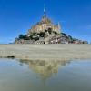 The abbey of Mont Saint-Michel during the day and reflecting in a pool of water.