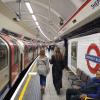 two students walking along the platform shepard's bush in london whle a train passes on the left