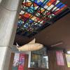A stained glass ceiling with a wooden fish sculpture hanging from it