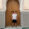 A Moroccan style door with Moroccan tile work, with a handsome blond man standing in the middle. 