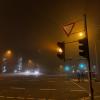 A foggy street with traffic lights and some cars
