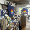 Shelves of LGBTQ books and resources with flags in the background