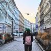 Two friends are walking the streets of Vienna, on a street centered between tall buildings encapsulating the scenery on the left and right.