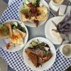 Photo from above of three plates filled with breakfast food, coffee cups, and plant on a small table