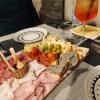 A table filled with Italian aperitivo dishes including cured meats, cheeses, olives, bruschetta, and bread, served with an Aperol Spritz at a restaurant in Milan.