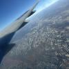 View outside of a plane window showing the Chicago metropolitan area, the right wing of a plane, and a blue sky.