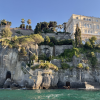 A lush cliff leading into blue water