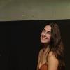 Beatriz Vasconcellos Neumann smiling in front of a black and white background.