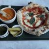 Pizza, tomato soup, and pickles on a tray.