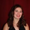 Sara Kurth smiling in front of a red background.