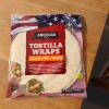 A bag of tortilla wraps labeled "American" rests on a wooden table.