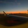 View from an airplane in Boston at Logan Airport, with the sunset and terminal visible outside.