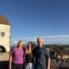 3 people stand on a hill with a castle in the background