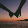Silhouette of holding hands in front of a sunset