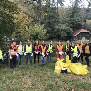 12 people wearing reflective vests standing behind a pile of full trash bags