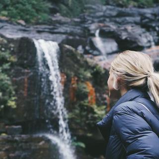 student wearing cold weather gear looking up towards a waterfall