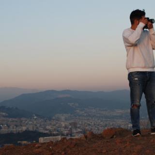 Christian Canizal holding up a camera in front of a sunset.