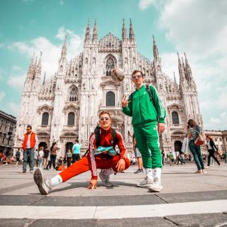 two students pose in jumpsuits for an iconic photo in front of Duomo di Milano with their soccer balls