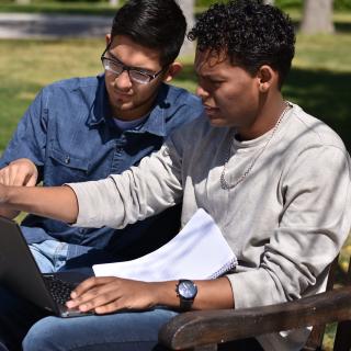 Two students studying on a bench together