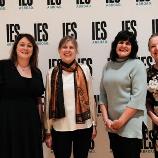 Four smiling women in front of a background that says IES Abroad