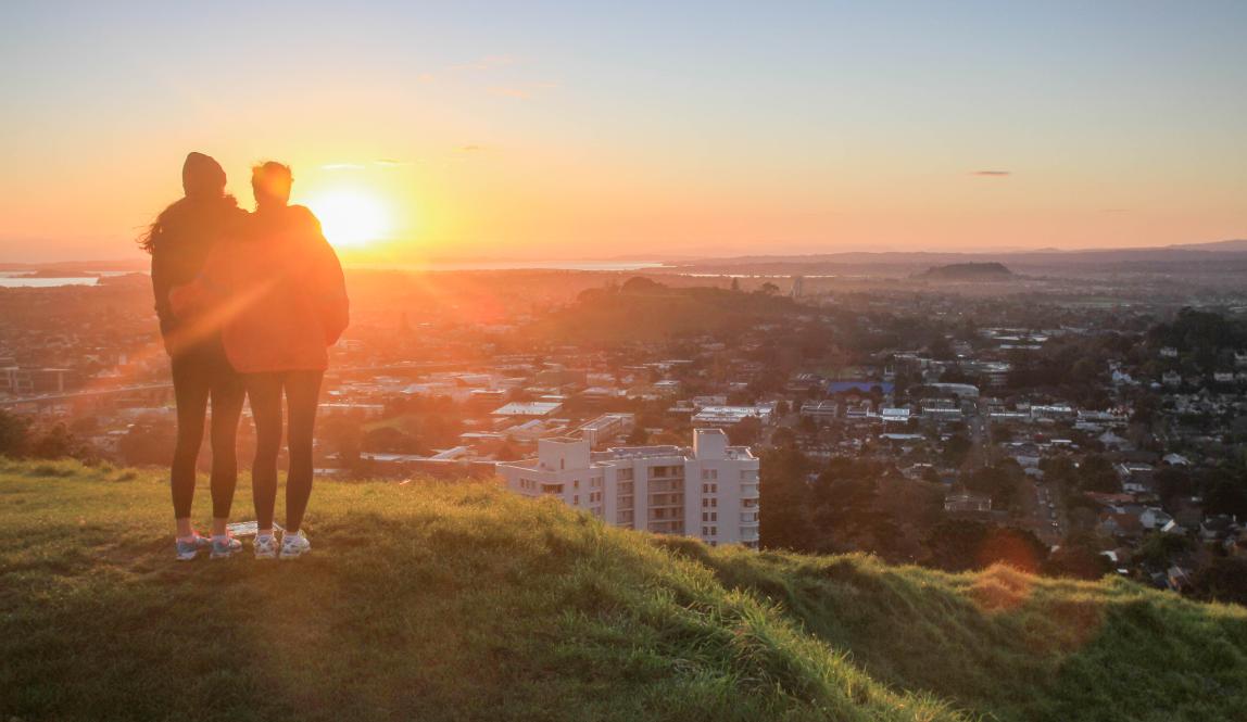 two students watch the sunset atop Mount Eden in Auckland