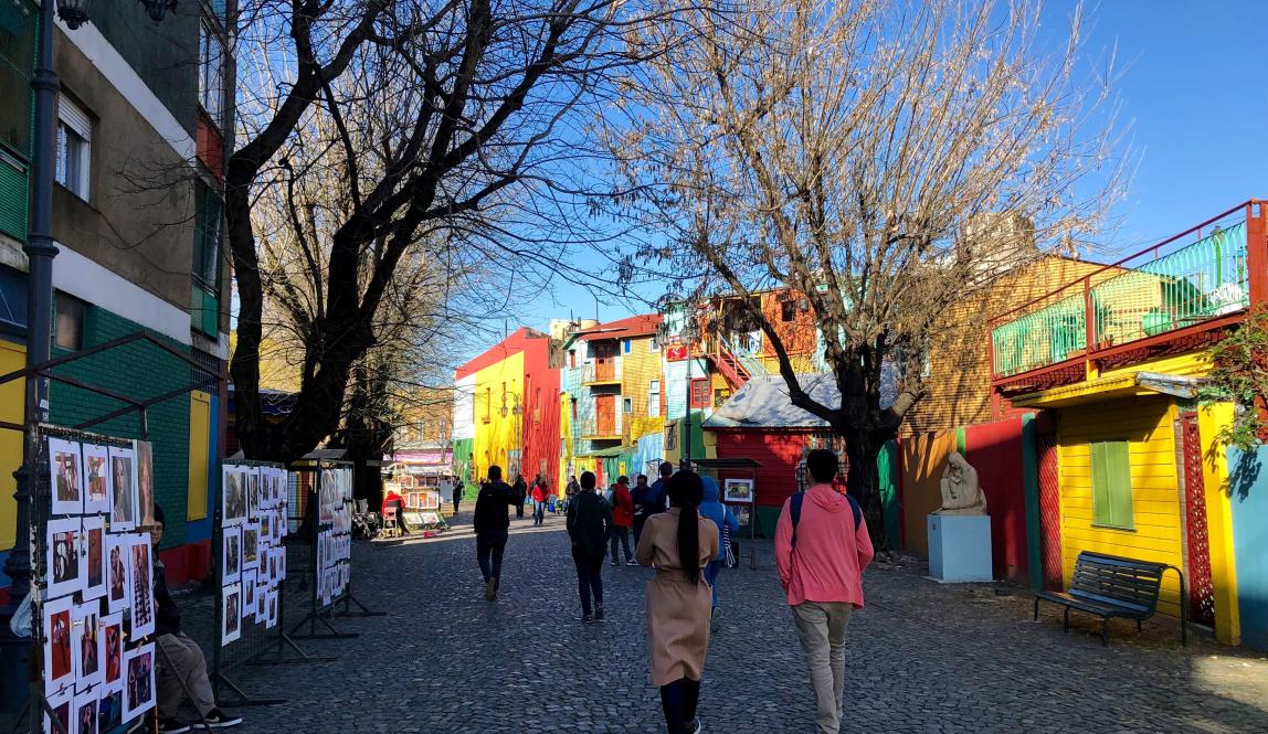 a group of students walk between the colorful buildings of La Boca, Buenos Aires