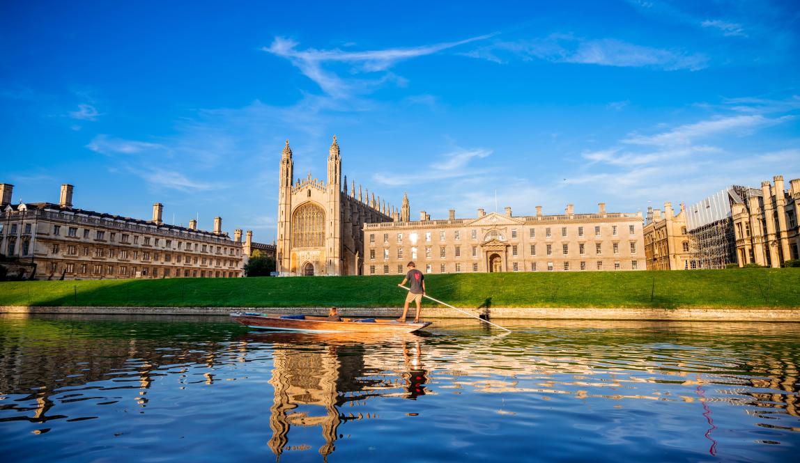 A landscape image of Kings College from across the Cam River. A group of people are punting down the river.